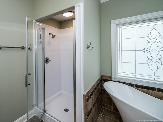 full bath with a freestanding bath, tile patterned flooring, a wainscoted wall, tile walls, and a shower stall