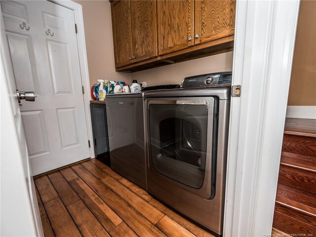 laundry room with dark wood-style flooring, cabinet space, and washer and clothes dryer