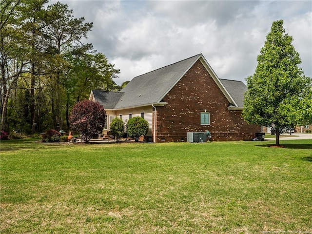 view of side of property featuring cooling unit, a yard, and brick siding