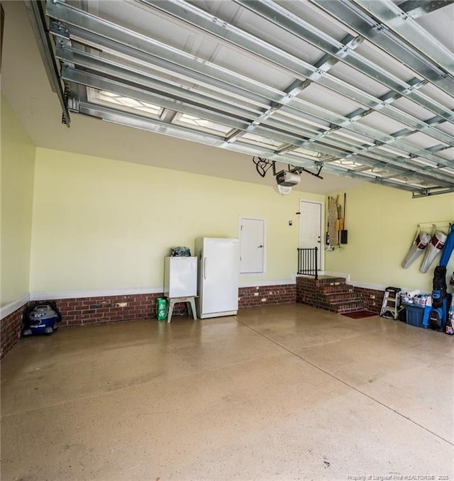 garage featuring freestanding refrigerator and a garage door opener