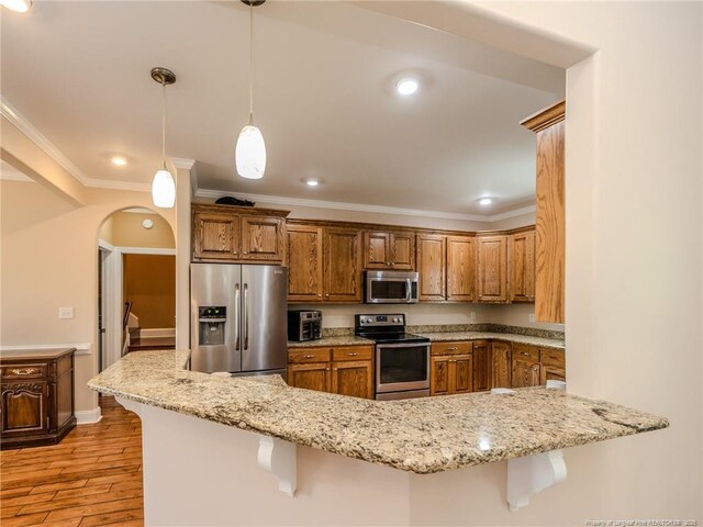 49 Alyssa Ct, Lumberton, NC 28360 - kitchen with stainless steel appliances, brown cabinets, a breakfast bar area, light wood-style flooring, and crown molding