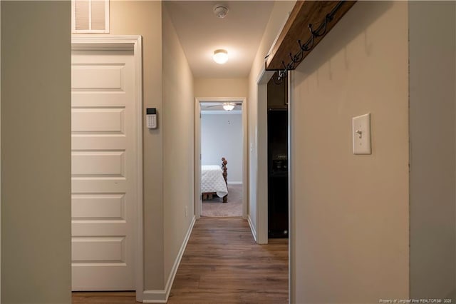 hallway featuring visible vents, baseboards, and wood finished floors