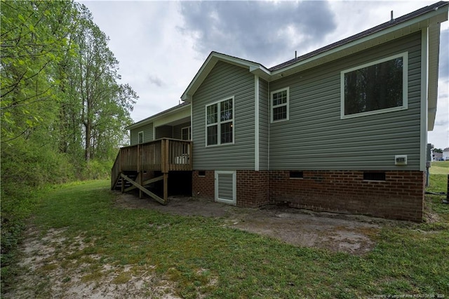 back of property with a yard, a deck, and crawl space