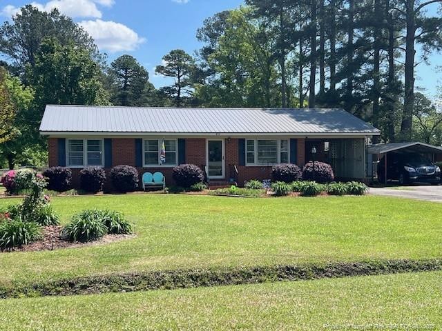 410 5th St, Bladenboro, NC 28320 - ranch-style home featuring brick siding, a front yard, metal roof, and a carport