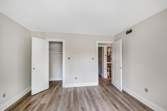 5804 Falls Of Neuse Rd Unit E, Raleigh, NC 27609 - unfurnished bedroom with light wood-style flooring, baseboards, and a closet