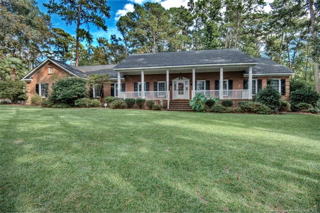 3248 Sids Mill Rd, Fayetteville, NC 28312 - view of front of home with covered porch, a front yard, and brick siding