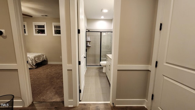 bathroom with visible vents, vanity, toilet, baseboards, and a stall shower
