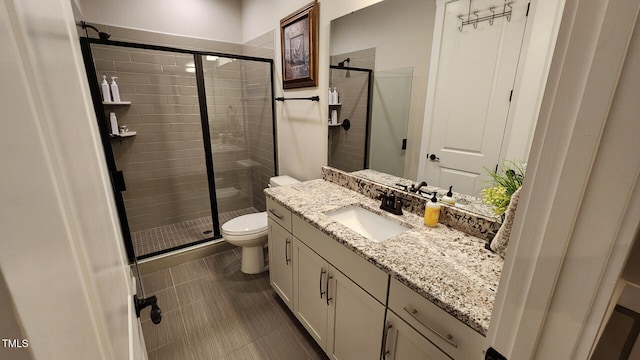 bathroom featuring vanity, a shower stall, and toilet