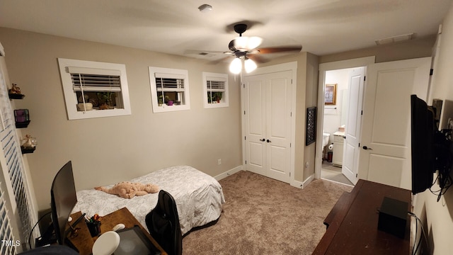carpeted bedroom featuring visible vents, baseboards, ensuite bathroom, and ceiling fan