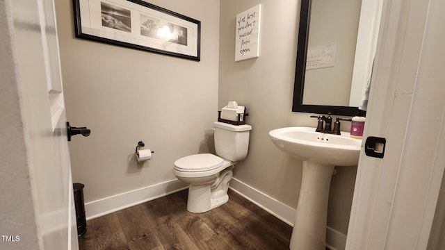 bathroom featuring toilet, baseboards, a sink, and wood finished floors