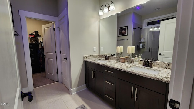 full bathroom with baseboards, a sink, a stall shower, and double vanity