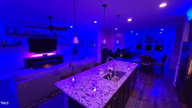 bar with a warm lit fireplace, recessed lighting, ceiling fan, and a sink