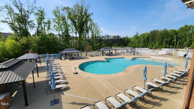 community pool with a gazebo, fence, and a patio area
