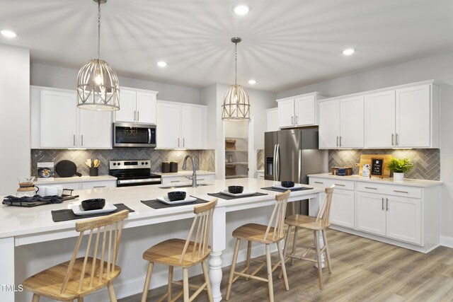 211 Faith Ave, Sanford, NC 27330 - kitchen featuring white cabinets, a breakfast bar, a sink, stainless steel appliances, and backsplash
