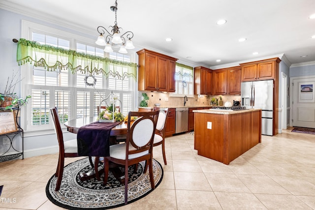 215 Terrell Dr, Rolesville, NC 27571 - kitchen featuring appliances with stainless steel finishes, ornamental molding, a chandelier, a center island, and brown cabinets