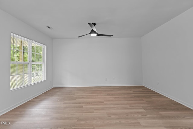 spare room featuring light wood-style floors, baseboards, a ceiling fan, and visible vents