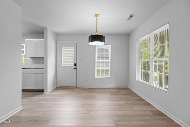 unfurnished dining area with baseboards, light wood-style flooring, and a wealth of natural light