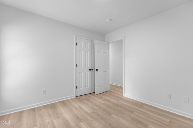 unfurnished bedroom featuring a closet, baseboards, and light wood-style floors
