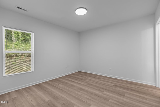empty room featuring baseboards, light wood-type flooring, and visible vents
