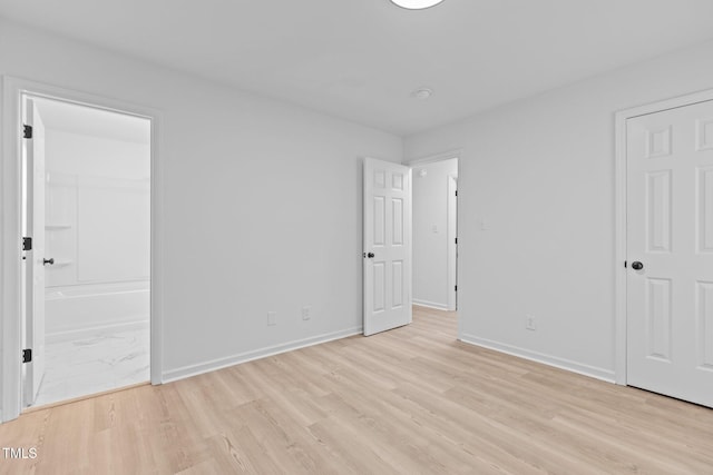 unfurnished bedroom with baseboards, light wood-type flooring, and connected bathroom