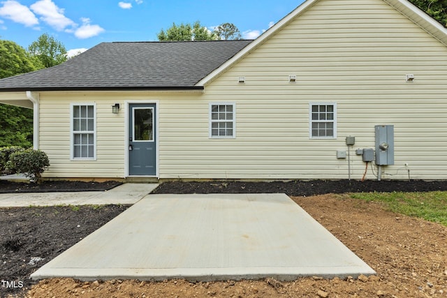 rear view of house featuring roof with shingles and a patio area