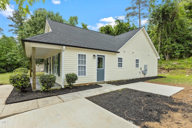 view of front of house with a shingled roof and a patio area
