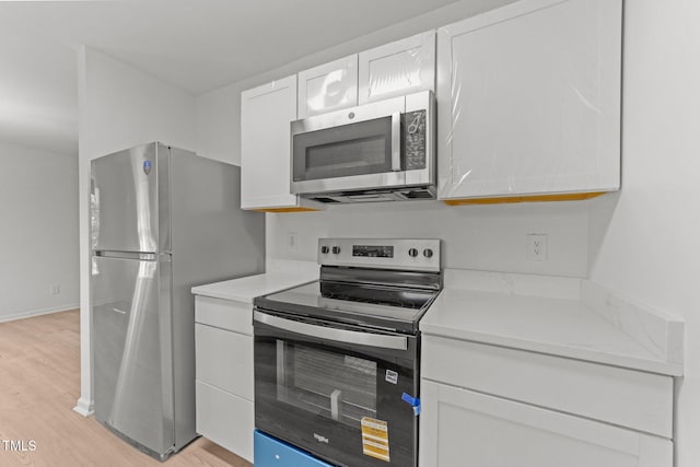 kitchen featuring light countertops, white cabinets, stainless steel appliances, and light wood finished floors