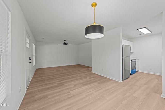 unfurnished living room with baseboards, ceiling fan, and light wood-style flooring