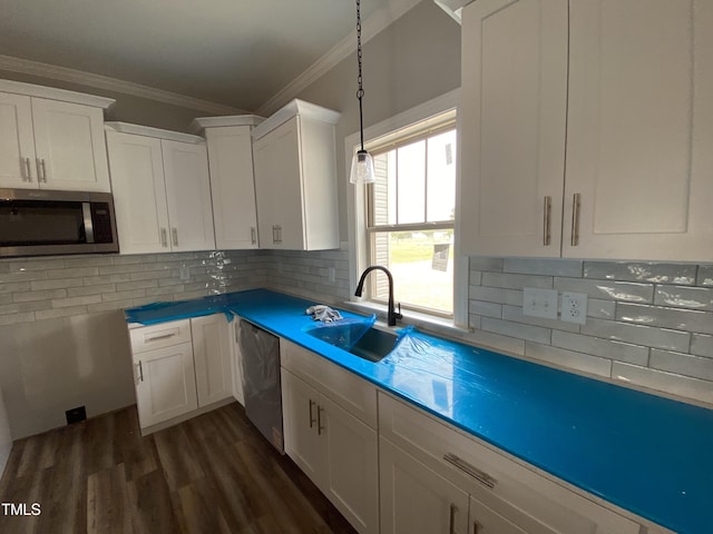 kitchen featuring a sink, appliances with stainless steel finishes, white cabinets, ornamental molding, and dark wood-style floors
