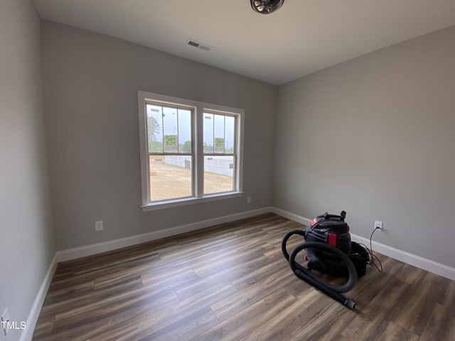 unfurnished room with wood finished floors, visible vents, and baseboards