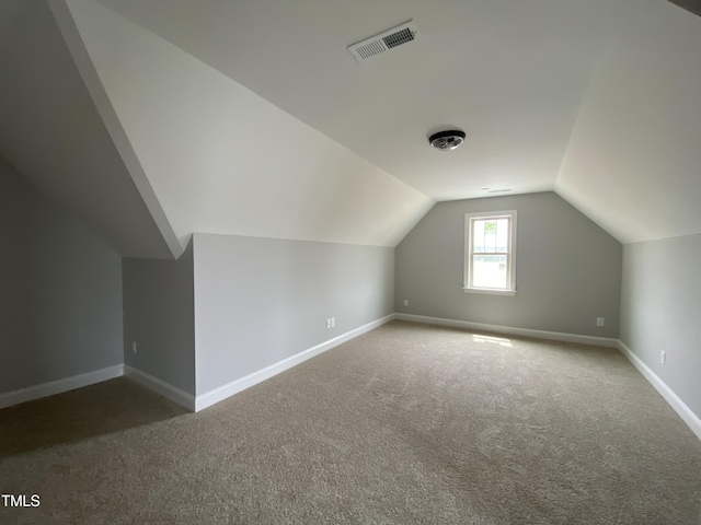 additional living space with baseboards, lofted ceiling, visible vents, and carpet