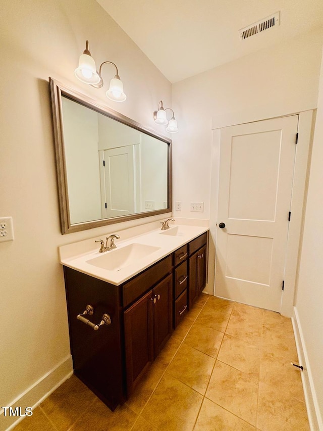 bathroom featuring a sink, visible vents, tile patterned floors, double vanity, and baseboards