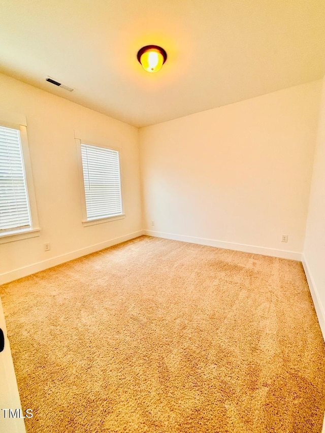 spare room featuring baseboards, visible vents, and light colored carpet