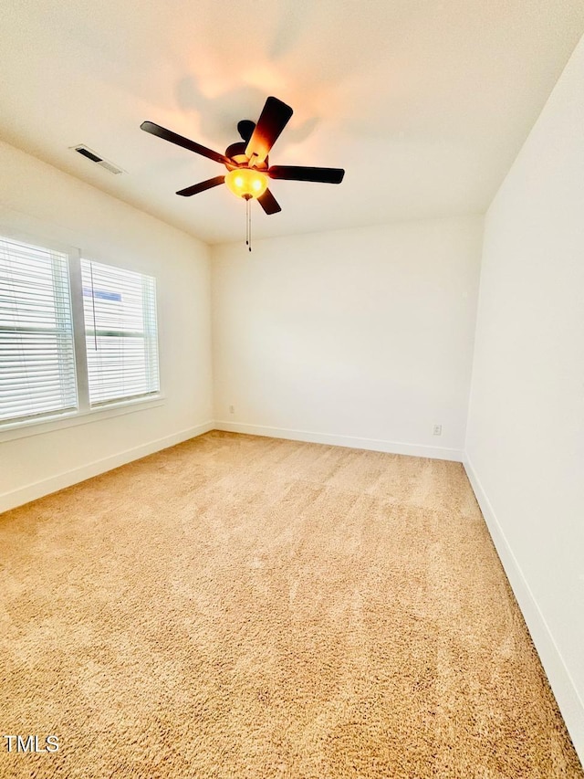 spare room with light colored carpet, visible vents, baseboards, and a ceiling fan