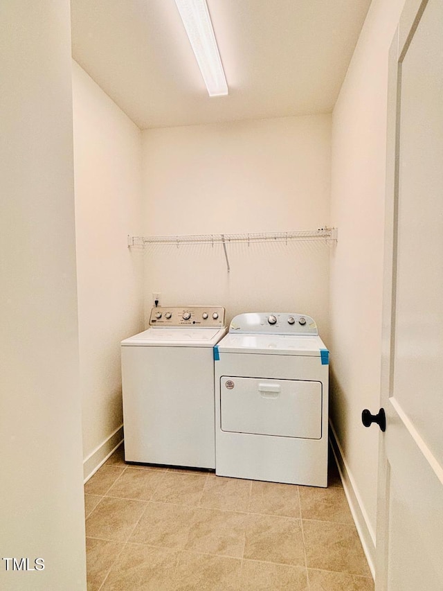 laundry room featuring baseboards, laundry area, light tile patterned floors, and independent washer and dryer