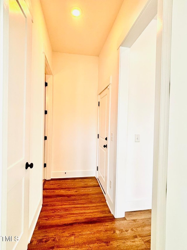 corridor featuring baseboards, recessed lighting, and wood finished floors