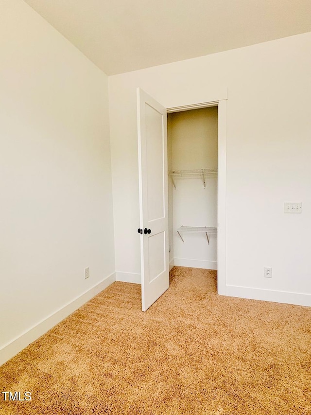 unfurnished bedroom featuring light carpet, baseboards, and a closet