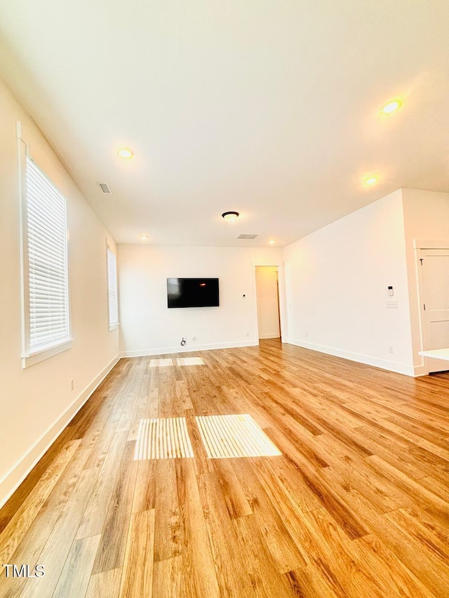 unfurnished living room featuring light wood-style flooring, baseboards, visible vents, and recessed lighting
