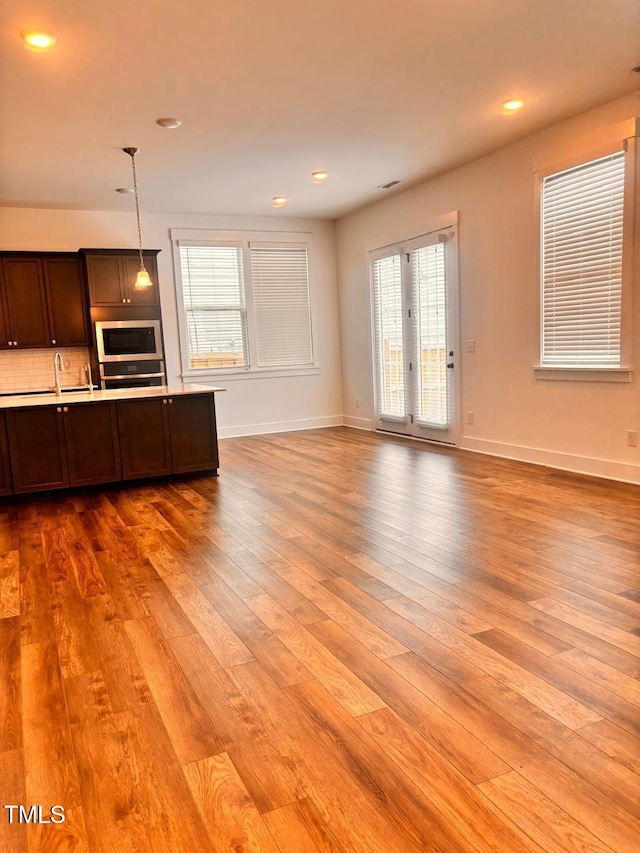 unfurnished living room featuring recessed lighting, baseboards, a sink, and hardwood / wood-style flooring