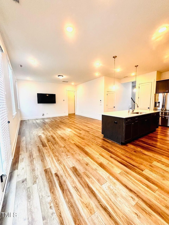 unfurnished living room with baseboards, recessed lighting, light wood-type flooring, and a sink