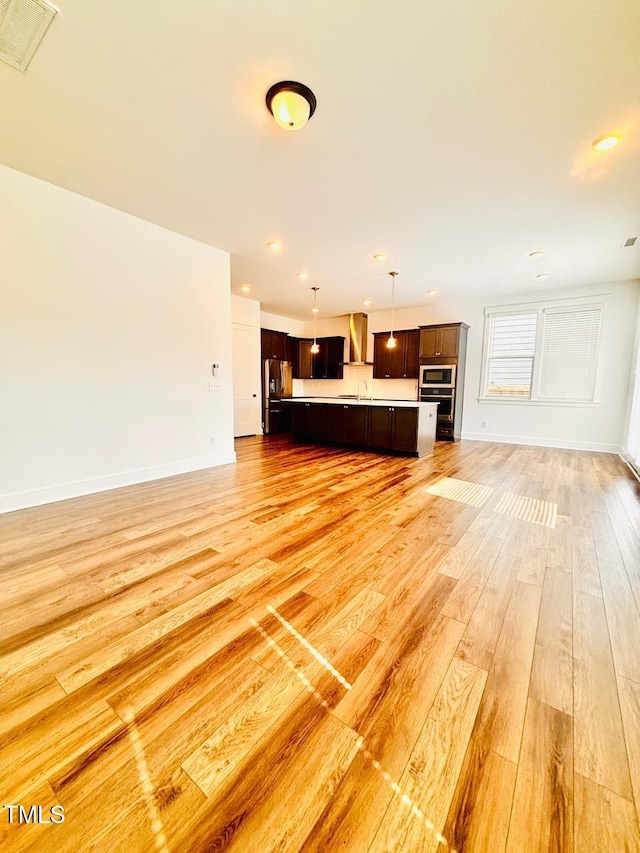 unfurnished living room featuring a sink, light wood finished floors, baseboards, and recessed lighting