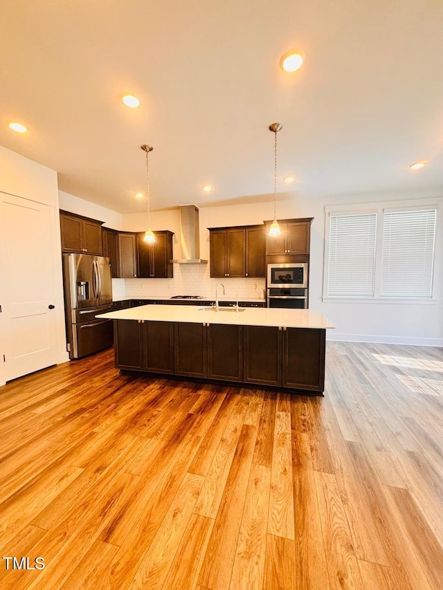 kitchen featuring dark brown cabinets, a large island, appliances with stainless steel finishes, and wall chimney exhaust hood