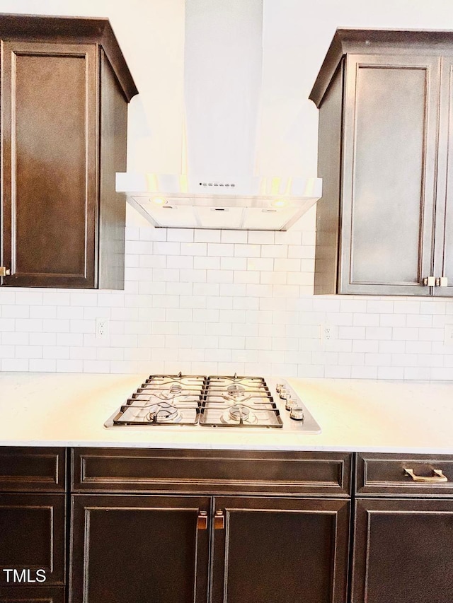 kitchen featuring light countertops, dark brown cabinets, range hood, and stainless steel gas cooktop