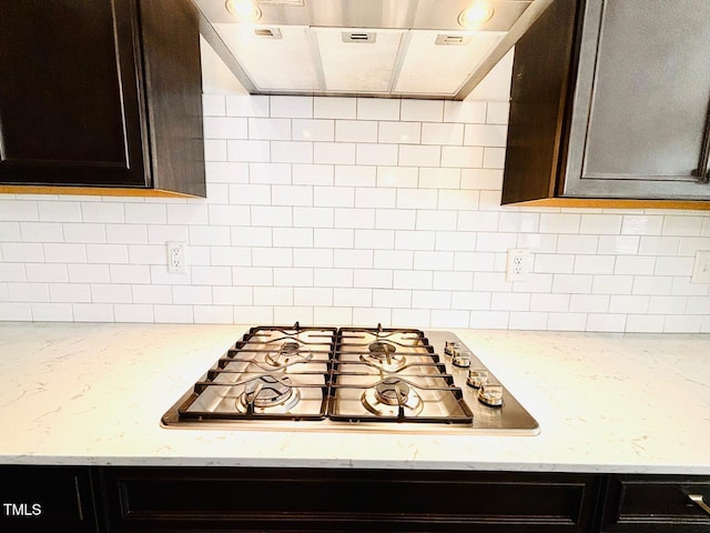kitchen with dark brown cabinets, extractor fan, stainless steel gas stovetop, decorative backsplash, and light stone counters
