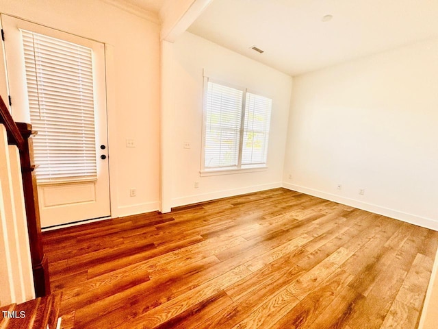 unfurnished room with visible vents, wood finished floors, and baseboards