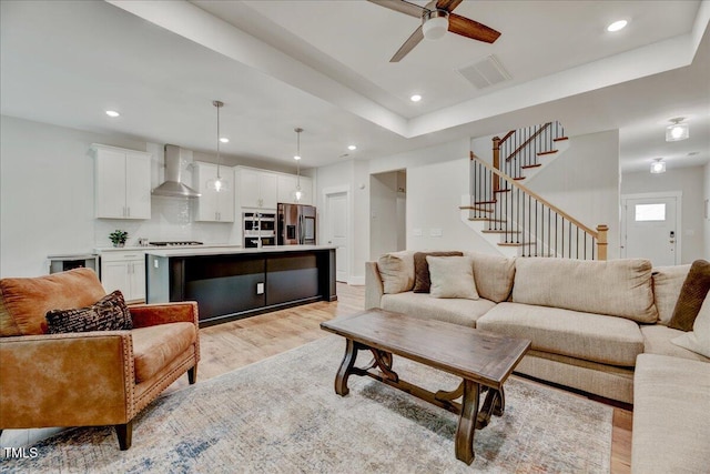 living room with a ceiling fan, stairs, light wood-style flooring, visible vents, and recessed lighting