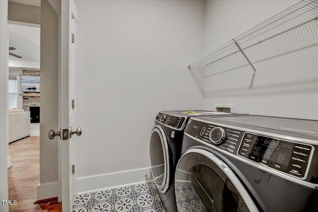 washroom with a stone fireplace, wood finished floors, laundry area, and independent washer and dryer
