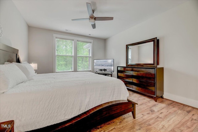 bedroom featuring a ceiling fan, baseboards, and light wood-style floors