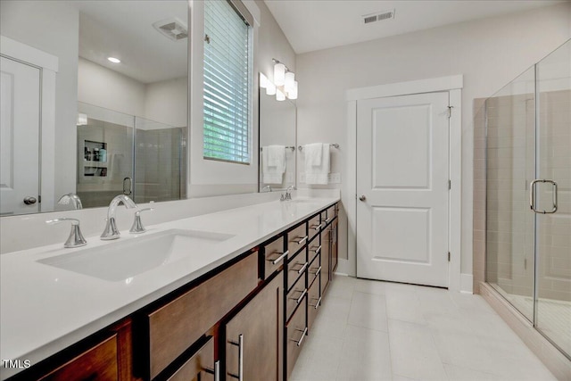 bathroom with a shower stall, a sink, visible vents, and double vanity