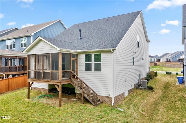 back of property with central AC, a sunroom, roof with shingles, and a yard